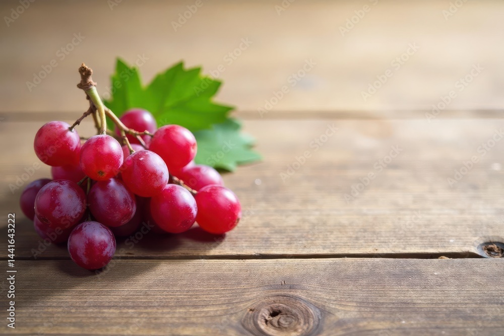 A cluster of vibrant red grapes rests on a rustic wooden surface, showcasing the freshness and natural beauty of the fruit.