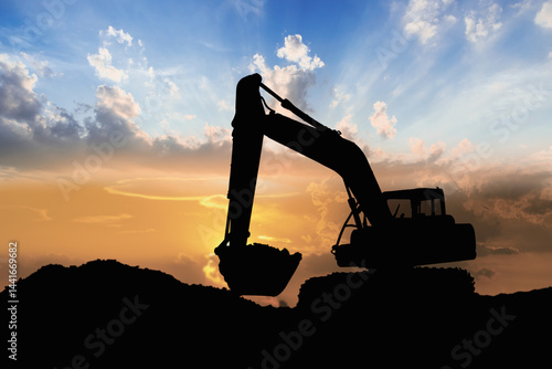 Crawler excavators silhouette are digging the soil in the construction site. With blue sky and clouds of on sunset background