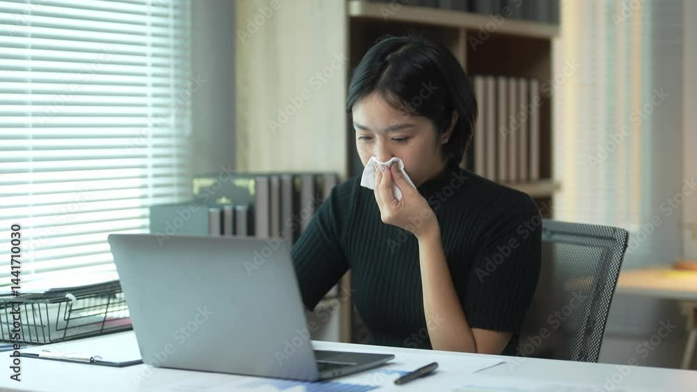A woman is sitting at a desk with a laptop open in front of her. She is wearing a black sweater and she is focused on her work A woman is sitting at a desk with a laptop open in front of her. She is wearing a black sweater and she is focused on her work