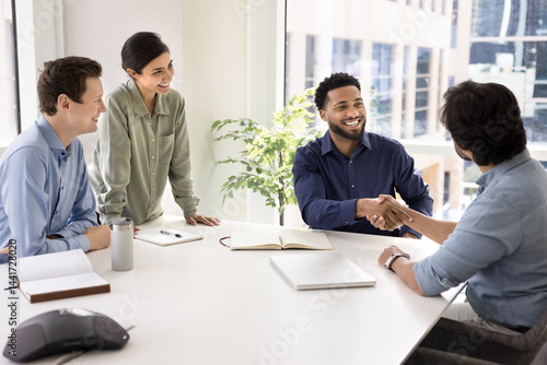 фотографія African businessman greeting client, starting negotiations in conference room, engaged in cooperation, shaking hands, accomplishing meeting successfully, achieving joint goal