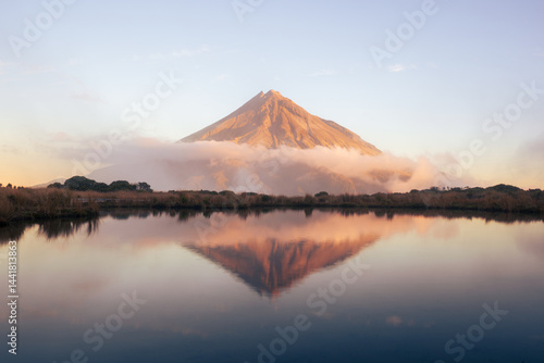 Mount Taranaki reflected in lake at sunrise, New Zealand volcanic landscape