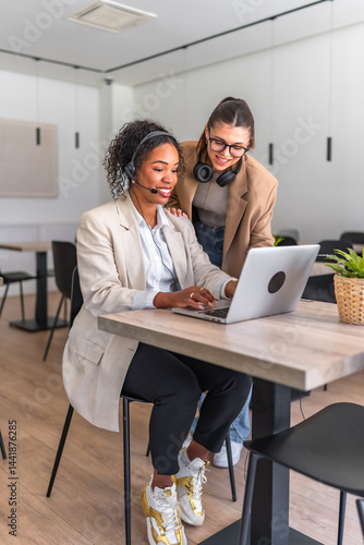 Customer service representatives working together on a laptop in a modern office
