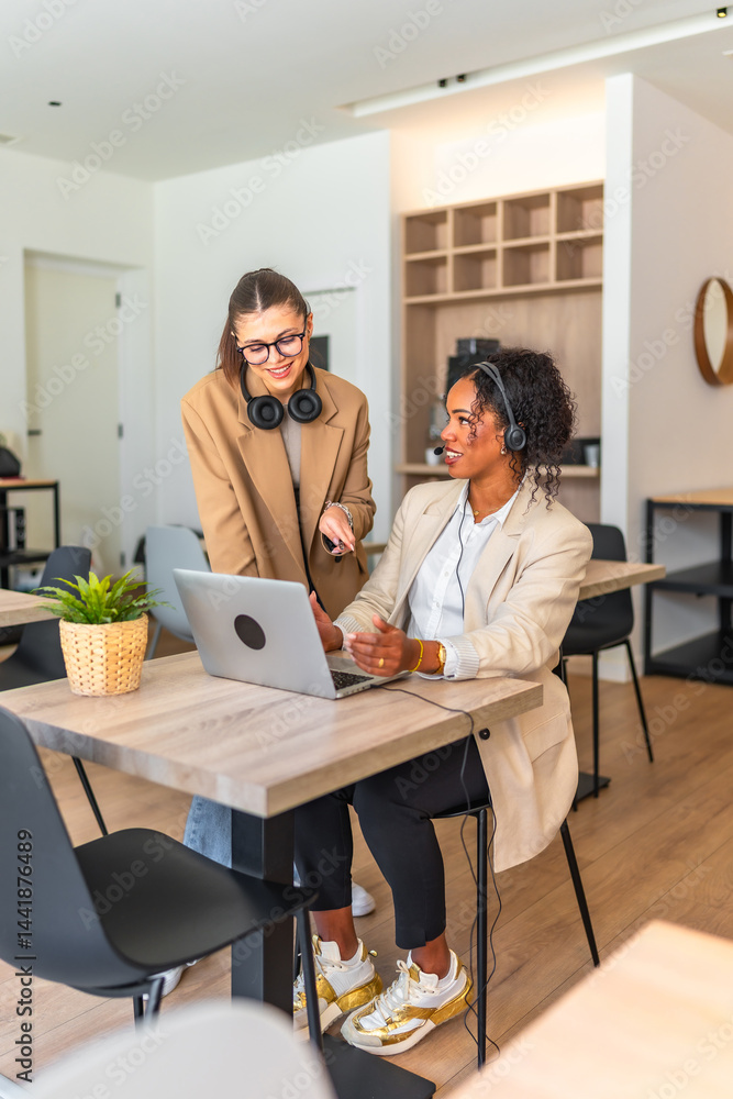 Two businesswomen collaborating on laptop in modern office