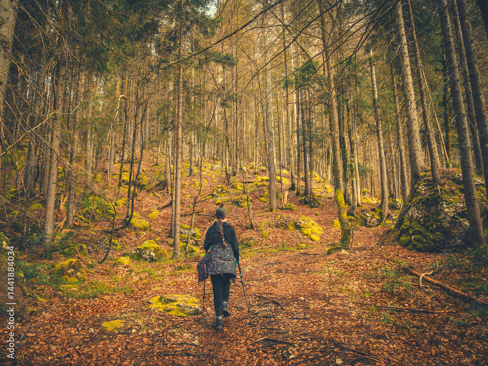 A teenage girl walks alone through a vibrant forest near Kranjska Gora, Slovenia. The path is surrounded by lush evergreen trees and the sky is overcast, creating a moody yet colorful atmosphere. A teenage girl walks alone through a vibrant forest near Kranjska Gora, Slovenia. The path is surrounded by lush evergreen trees and the sky is overcast, creating a moody yet colorful atmosphere.