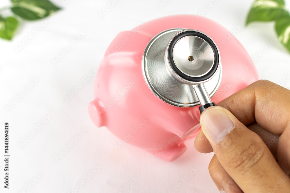 豚の貯金箱と手と聴診器。家計のイメージ