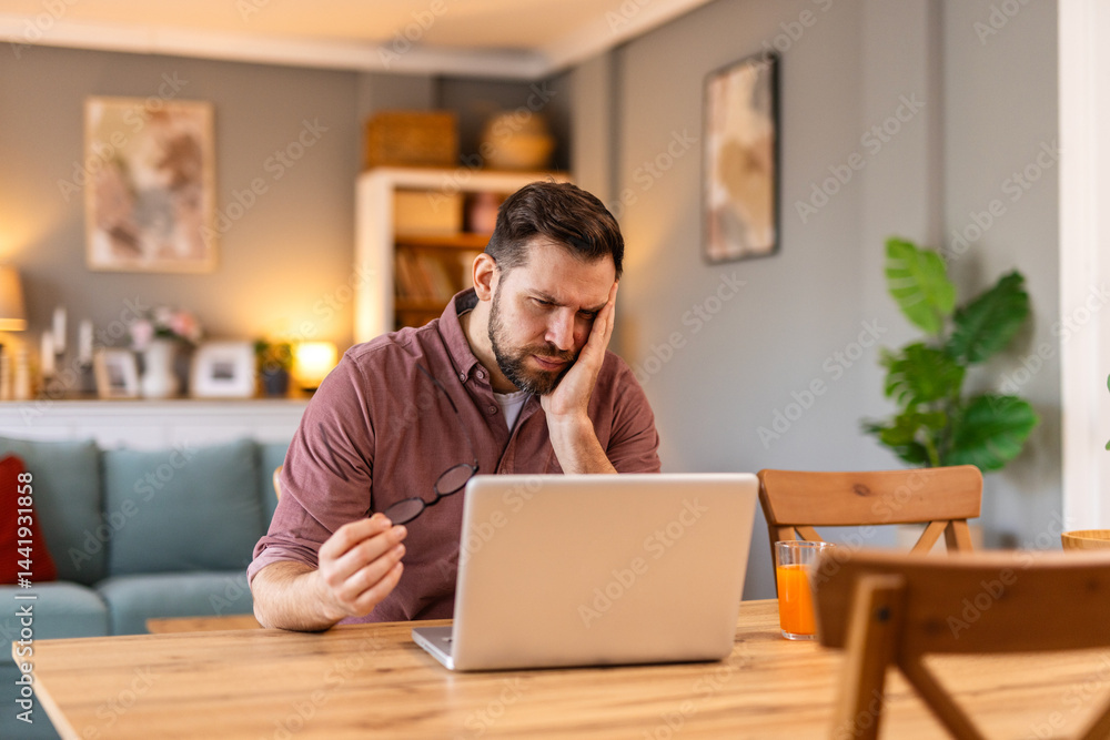 Young man working remotely on his laptop at a wooden table. Cozy home interior with warm lighting, bookshelves, and a bowl of fruits, reflecting a healthy, productive lifestyle. Young man working remotely on his laptop at a wooden table. Cozy home interior with warm lighting, bookshelves, and a bowl of fruits, reflecting a healthy, productive lifestyle.
