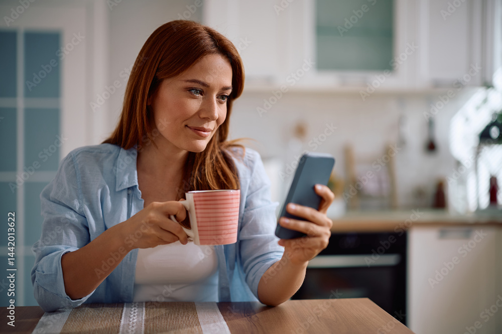 Happy woman texting on mobile phone while having cup of tea at home. Happy woman texting on mobile phone while having cup of tea at home.
