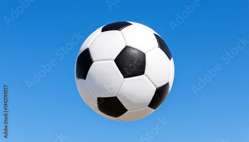Classic black and white soccer ball soaring against clear blue sky, evoking sense of excitement and playfulness
