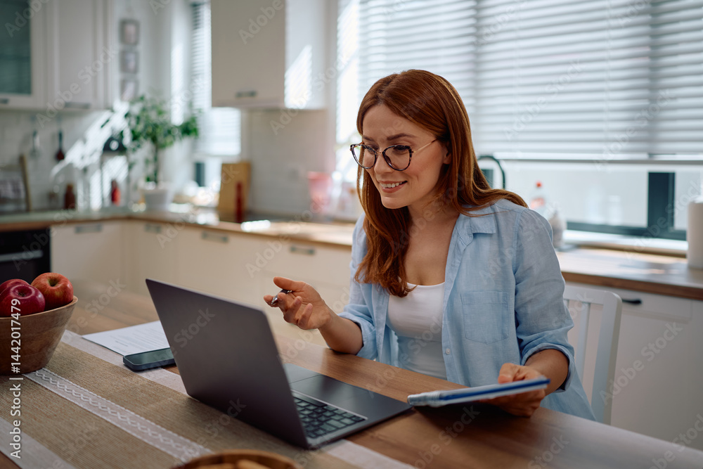 Female entrepreneur talking while making video call over laptop at home. Female entrepreneur talking while making video call over laptop at home.