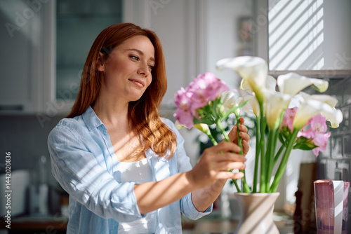 Fotografie Smiling woman decorating her home with flowers.