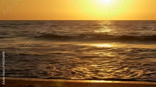 Serene ocean sunset scene with golden sunlight reflecting on gentle waves reaching the sandy shore