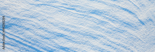 Obraz na płótnie Beautiful winter background with snowy ground. Natural snow texture. Wind sculpted patterns on snow surface. Wide panoramic texture for background and design. w salonie
