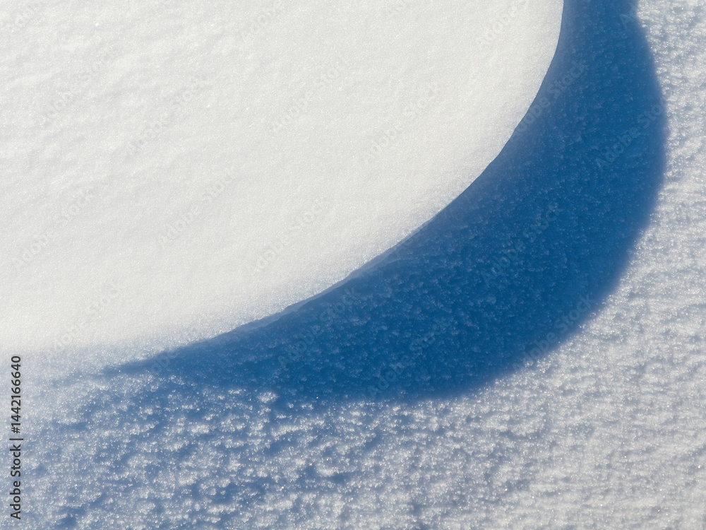 Beautiful winter background with snowy ground. Natural snow texture. Wind sculpted patterns on snow surface. Closeup top view with copy space.