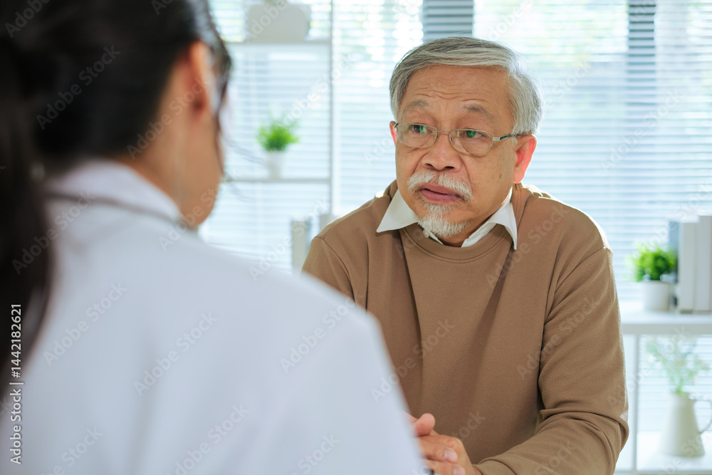 Doctor Reviewing Medical File While Interviewing Elderly Patient at Clinic or Hospital Doctor Reviewing Medical File While Interviewing Elderly Patient at Clinic or Hospital