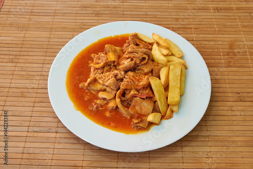 Obraz na płótnie A plate of food with meat and potatoes. The meat is covered in sauce and the potatoes are cut into small pieces w salonie