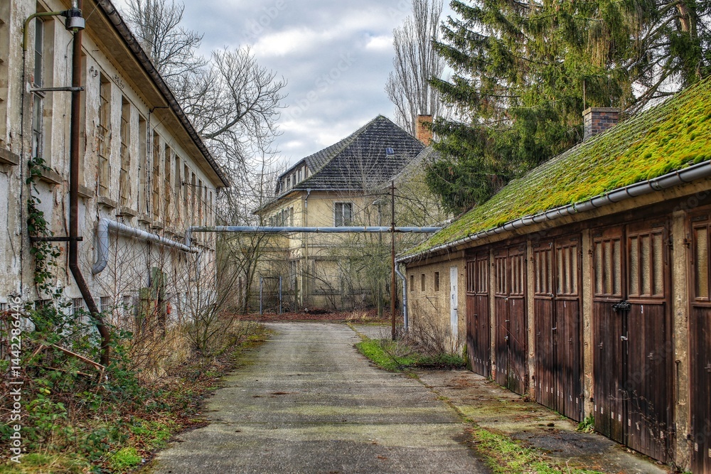 Abandoned courtyard buildings with weathered facades and overgrown garages