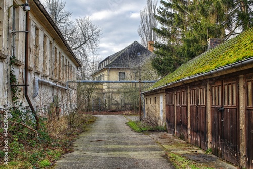 Obraz na płótnie Abandoned courtyard buildings with weathered facades and overgrown garages w salonie