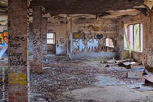 Obraz na płótnie Abandoned brick interior filled with graffiti, fallen debris, and decaying structural walls w salonie