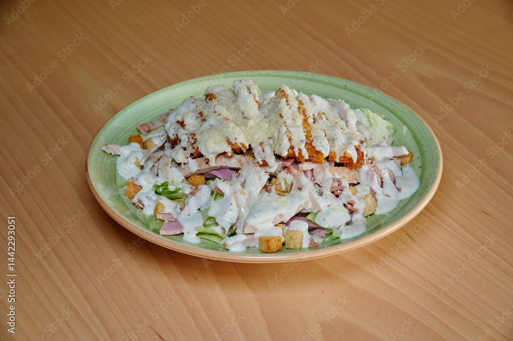 A plate of food with a green plate and a white sauce. The food is chicken and vegetables