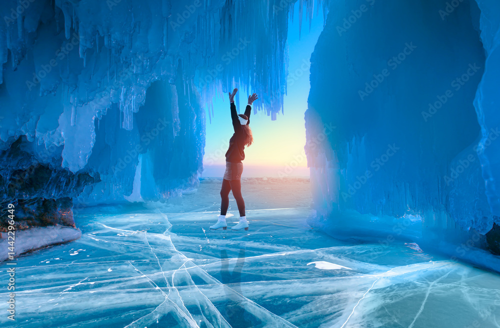 Fototapeta premium A young happy woman is skating on the transparent ice of the frozen Lake Baikal on a sunny winter day - Lake Baikal