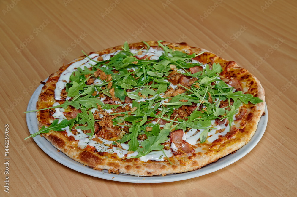 A pizza with spinach and bacon on top. It is sitting on a white plate. The pizza is cut into slices