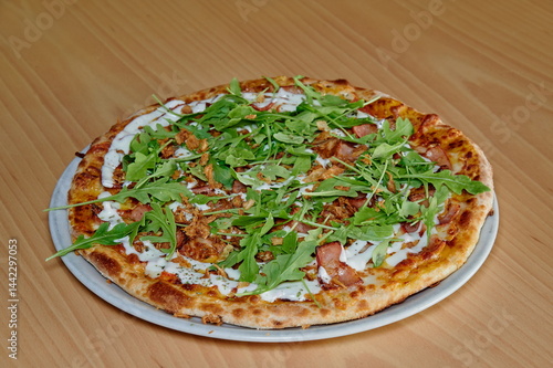Obraz na płótnie A pizza with spinach and bacon on top. It is sitting on a white plate. The pizza is cut into slices w salonie