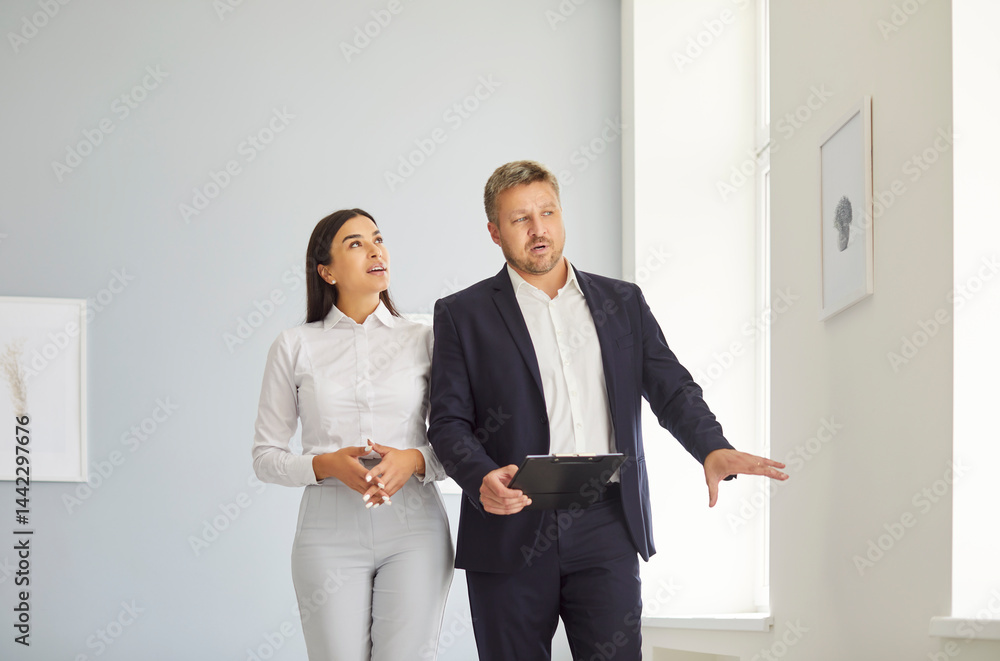 Expert realtor presenting to young woman bright spacious real estate, telling about progress of construction works or future design. Female client exploring options of house for purchase or rent.
