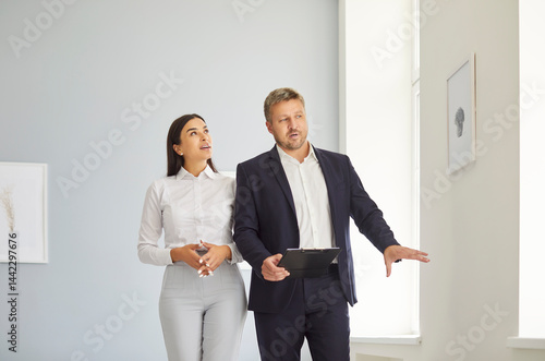 Obraz na płótnie Expert realtor presenting to young woman bright spacious real estate, telling about progress of construction works or future design. Female client exploring options of house for purchase or rent. w salonie
