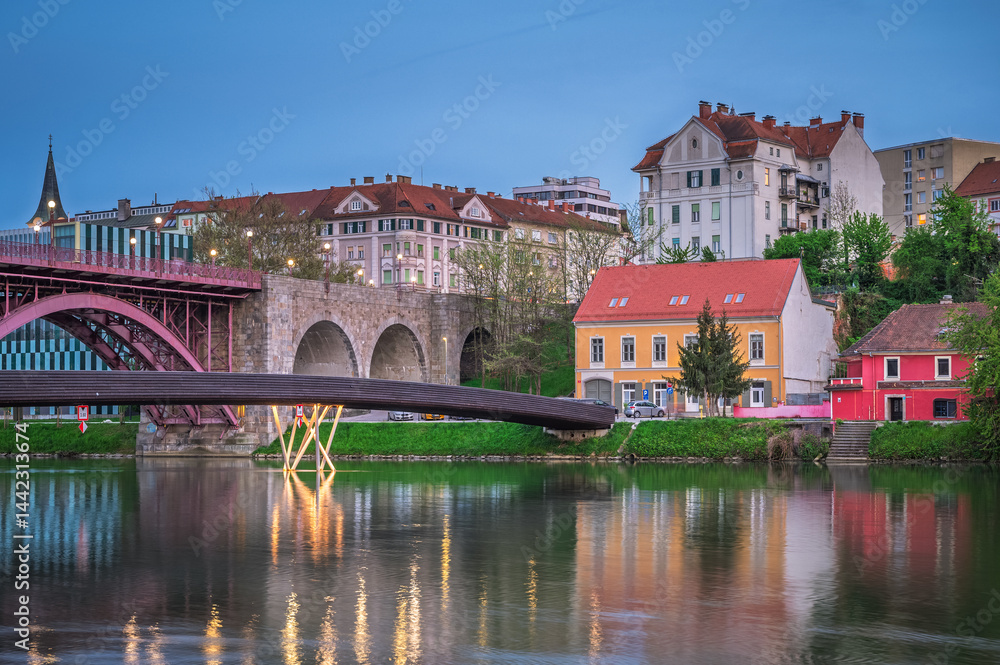 Scenic view of Maribor along the Drava River during spring with historic buildings and modern architecture