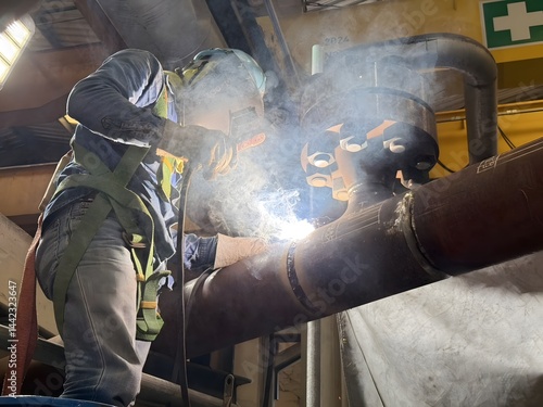 Industrial Welder at Work with Sparks and Smoke – Factory Pipe Welding Scene. Welder in safety gear working on a steel pipe in a factory. Captures real-time sparks, smoke, and intense focus