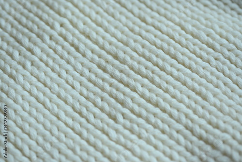 white texture of knitted wool fabric as a background, white smooth symmetrical lines of hand-knitted needlework pattern