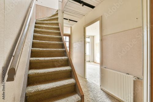 Obraz na plátně A view of a cozy indoor staircase leading to the upper floor, featuring beige carpeting and soft light illuminating the hallway