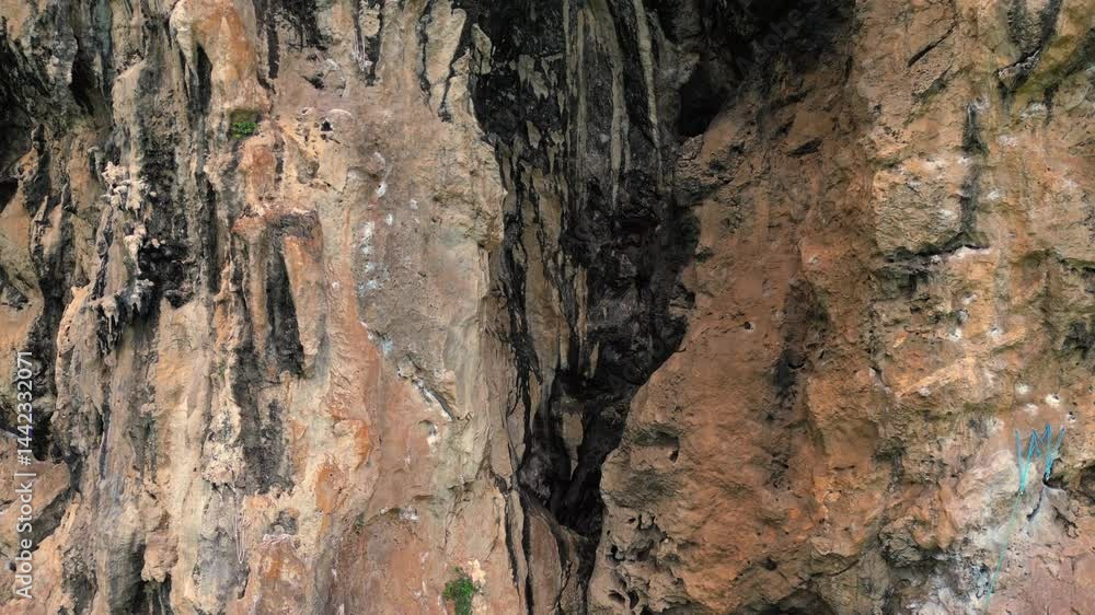 Rock climber resting during a difficult climb on Rai Leh beach cliff in Thailand. Smooth aerial view flight lift off raise up drone Rock climber resting during a difficult climb on Rai Leh beach cliff in Thailand. Smooth aerial view flight lift off raise up drone