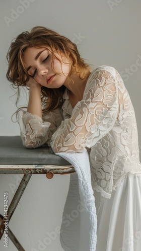 Obraz na płótnie Girl in white lace dress sitting on a chair, leaning on her arm, in a calm environment. Useful for fashion, style, relaxation. w salonie