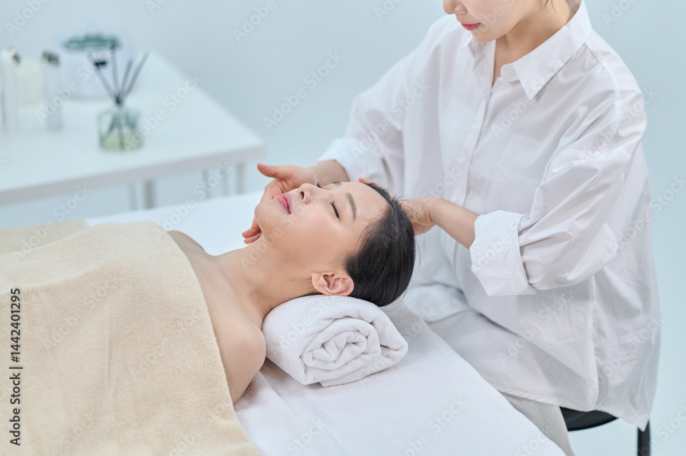 Obraz premium Female Spa Therapist Giving Head Massage to Woman in Wellness Center