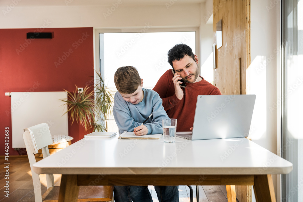 Father and son spending quality time together at home with a laptop and notebook Father and son spending quality time together at home with a laptop and notebook
