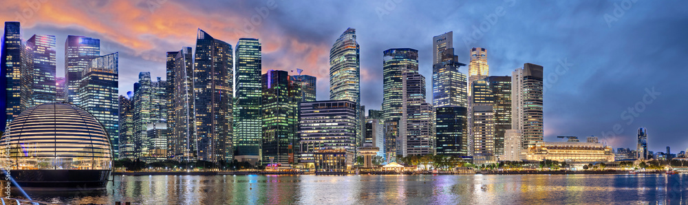 Fototapeta premium Singapore CBD City Skyline on the river at Sunset with vibrant colours of the high-rise apartment and office towers with the beautiful colours of the sky. Panorama view of Singapore CBD buildings