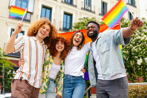 Happy multi ethnic friends celebrating lgbt pride month waving rainbow flags