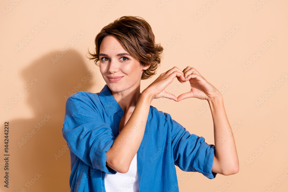 Portrait of young employee young woman created foundation donate for poor people show heart gesture isolated on beige color background