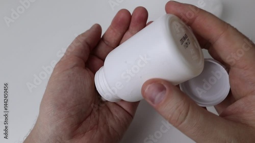Hands on white background pour L-theanine vitamins from the jar onto the palm of the hand