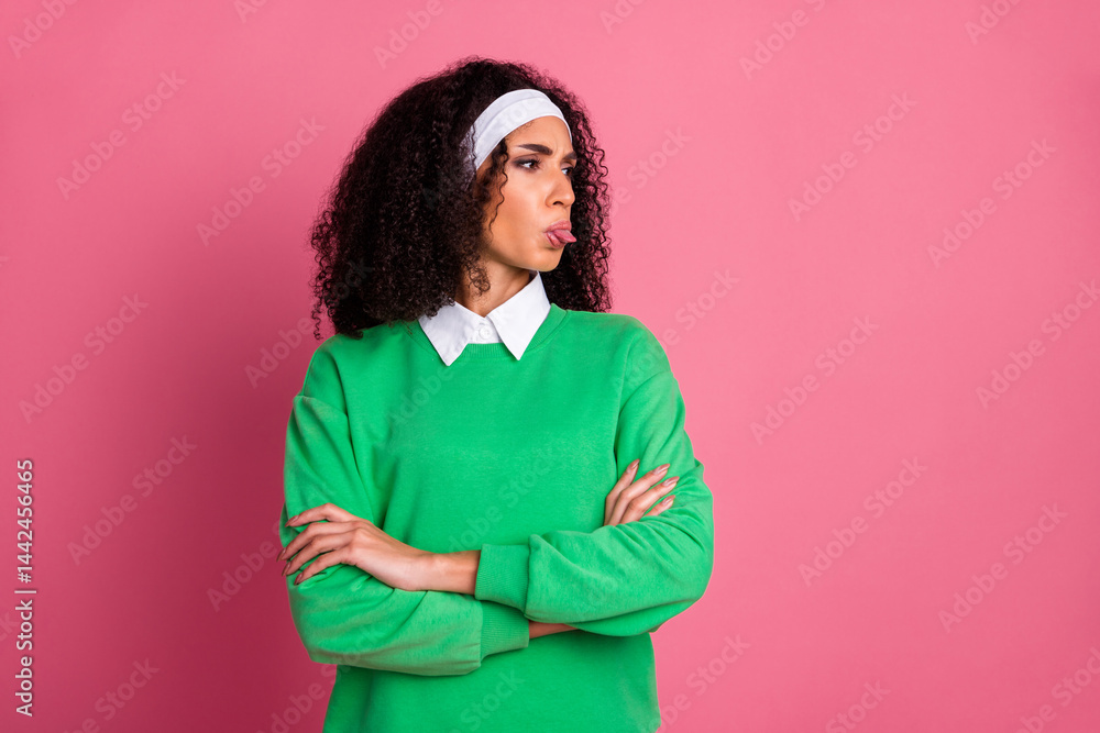 Obraz premium Stylish young woman in green pullover making playful face while posing against vibrant pink background