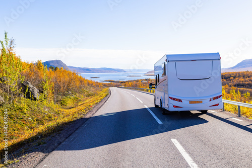 Obraz na płótnie Motorhome driving on a scenic road in Kiruna, Sweden, with autumn foliage and beautiful lake views. w salonie