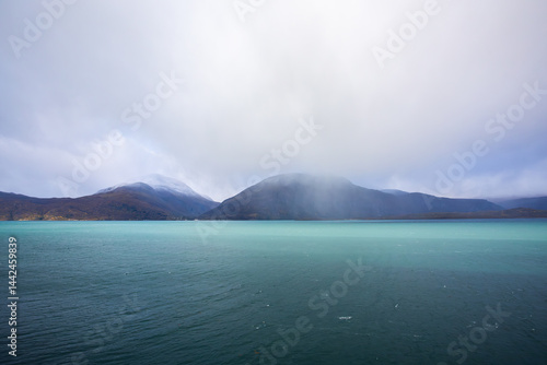 Obraz na płótnie Autumn landscape of the Lyngen Alps in Northern Norway with snowy peaks, dramatic clouds, and a tranquil fjord. w salonie