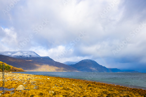 Obraz na płótnie Autumn landscape of the Lyngen Alps in Northern Norway with snowy peaks, dramatic clouds, and a tranquil fjord. w salonie