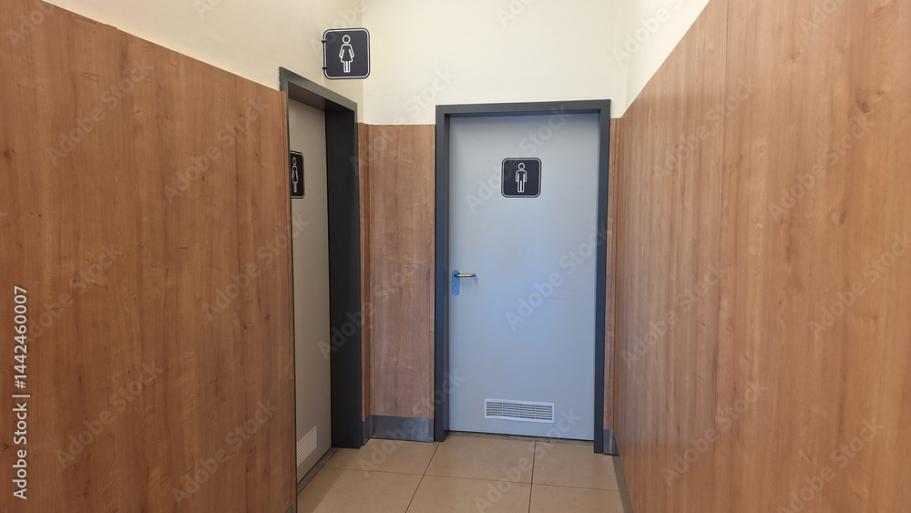 Public restroom entrance in modern facility with light wood paneling Public restroom entrance in modern facility with light wood paneling