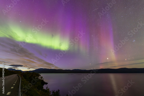Obraz na płótnie Northern lights in Kiruna, Sweden, reflecting on calm water in September with stars and forest in the background. w salonie