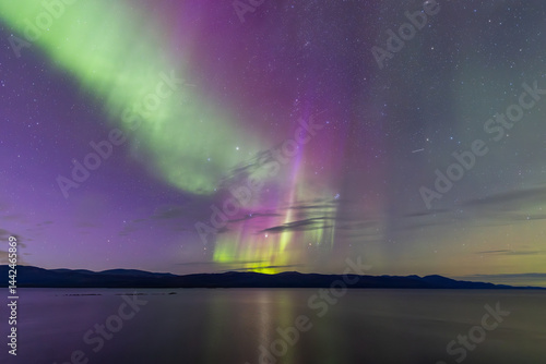 Obraz na płótnie Northern lights in Kiruna, Sweden, reflecting on calm water in September with stars and forest in the background. w salonie