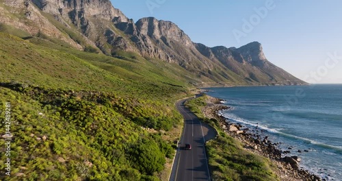 Spectacular aerial view of a winding road next to unspoilt beaches and a majestic mountain range in Cape Town’s stunning coastal landscape, popular tourist destination in South Africa