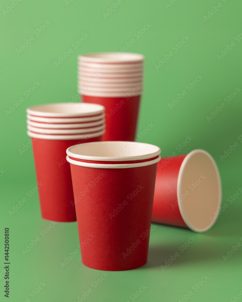Disposable red paper cups on a green closeup, mockup. No plastic and sustainable Christmas