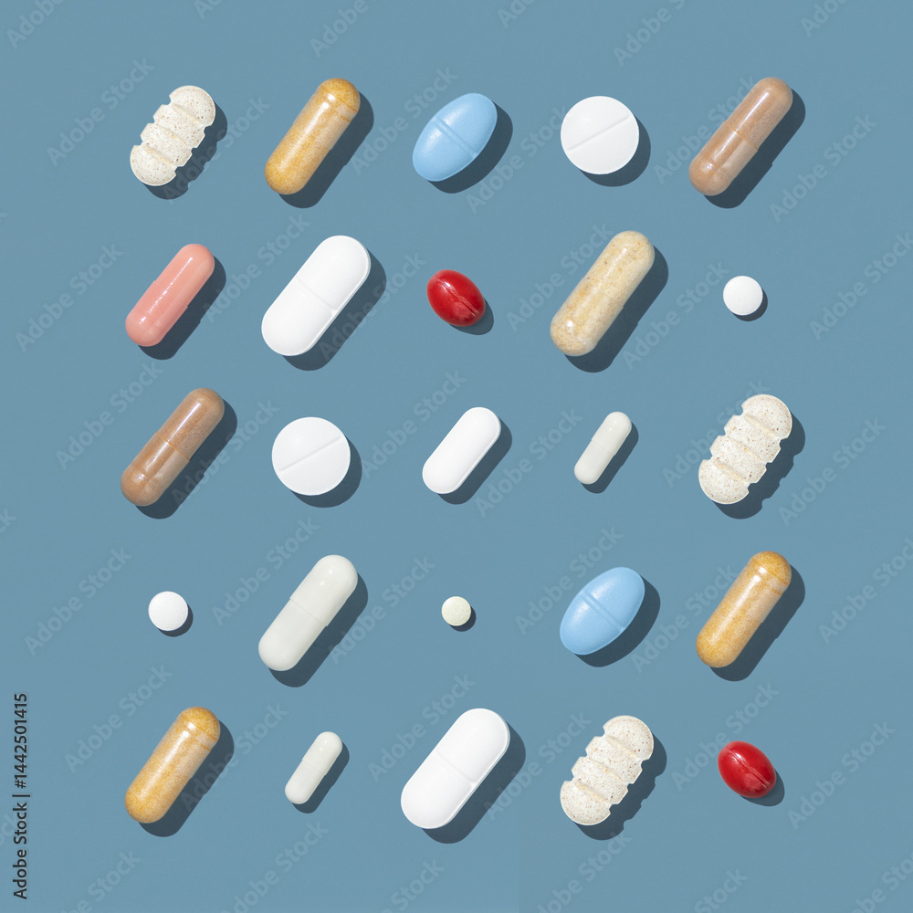 Medical capsules and pills in a lines on blue top view, hard shadow. Medicine and healthcare